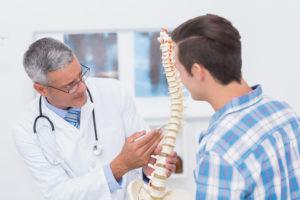 Doctor showing anatomical spine to his patient in medical office
