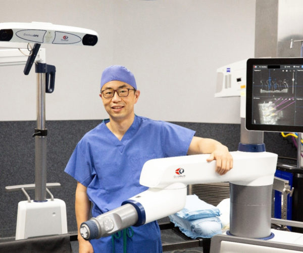 Dr Lu standing next to ExcelsiusGPS arm